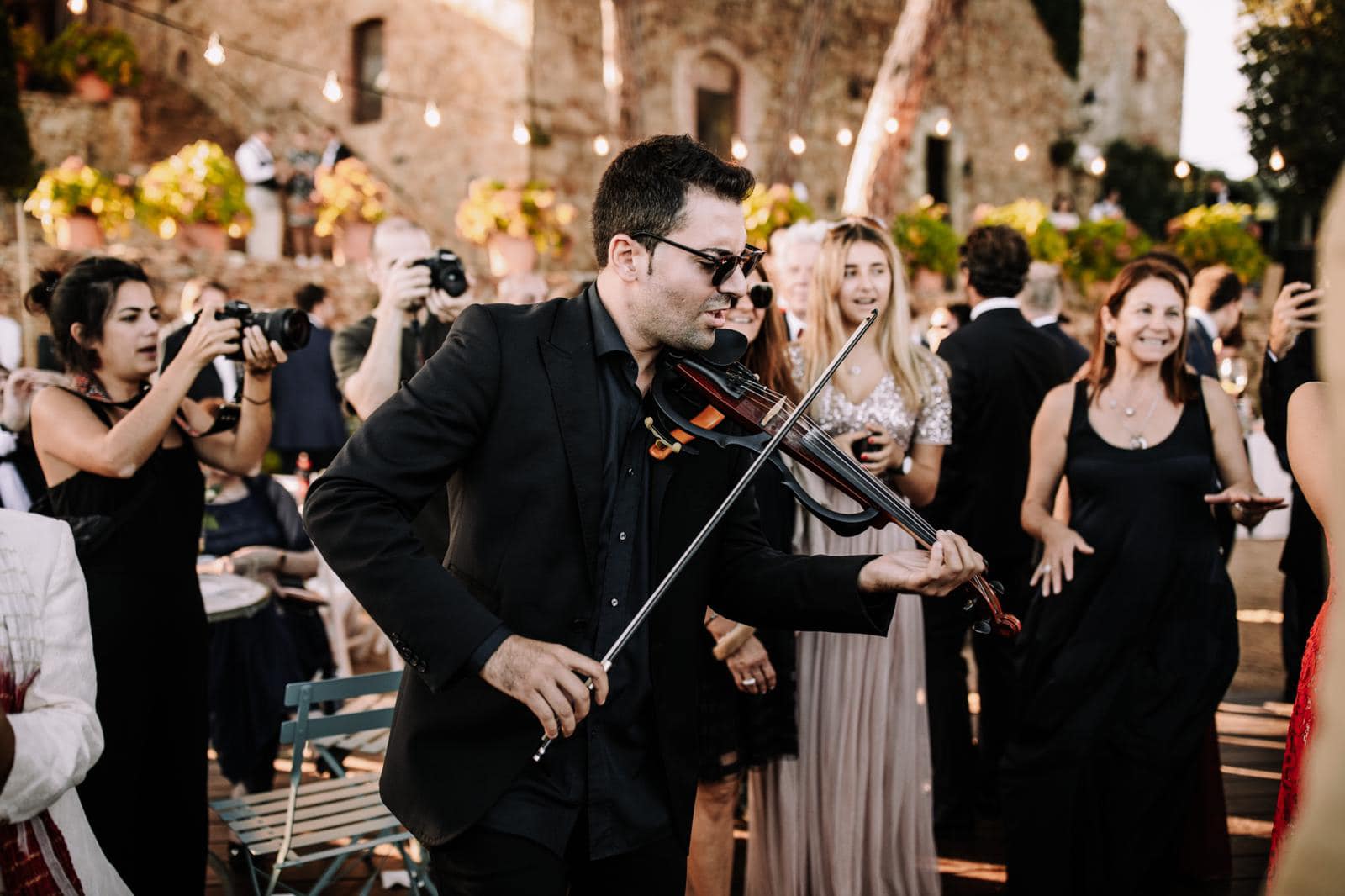 Violinista tocando en una boda elegante durante la ceremonia con invitados emocionados en exterior