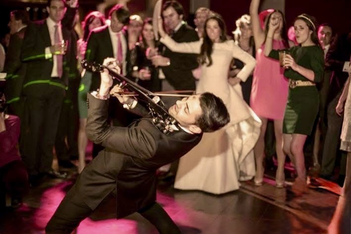 Violín eléctrico en barra libre con ambiente de fiesta elegante, invitados bailando y grabando con el móvil