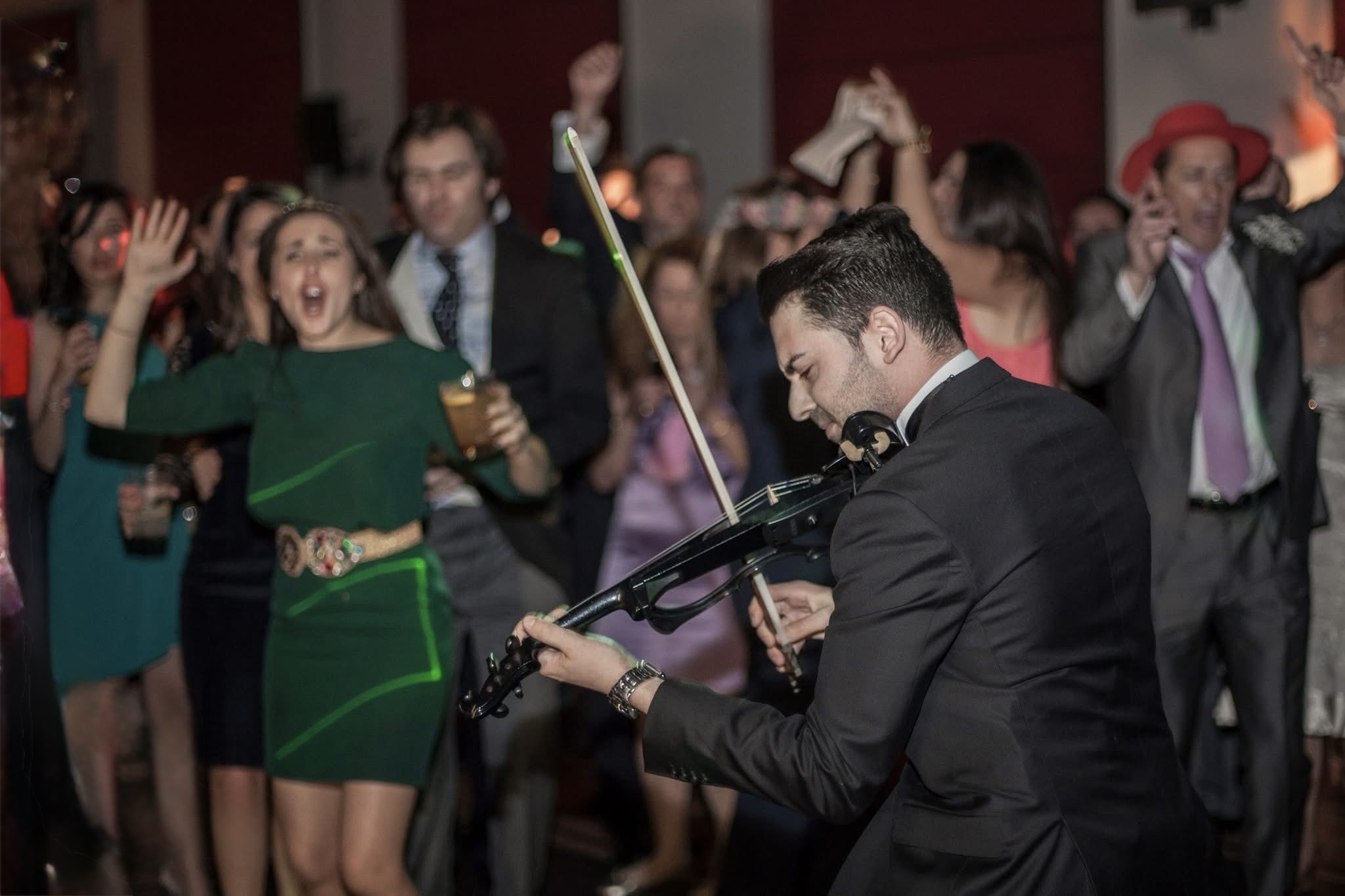Lolo Alonso tocando el violín eléctrico durante una barra libre con invitados levantando las manos